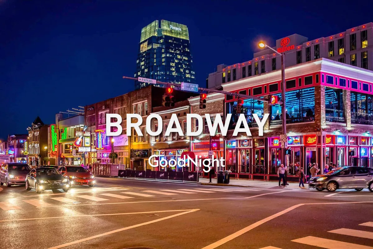 A lively Nashville streetscape at night, featuring glowing neon signs, bustling crowds, and high-rise buildings. The street is filled with people enjoying the vibrant nightlife, echoing the energy of Broadway's honky-tonks and live music venues.