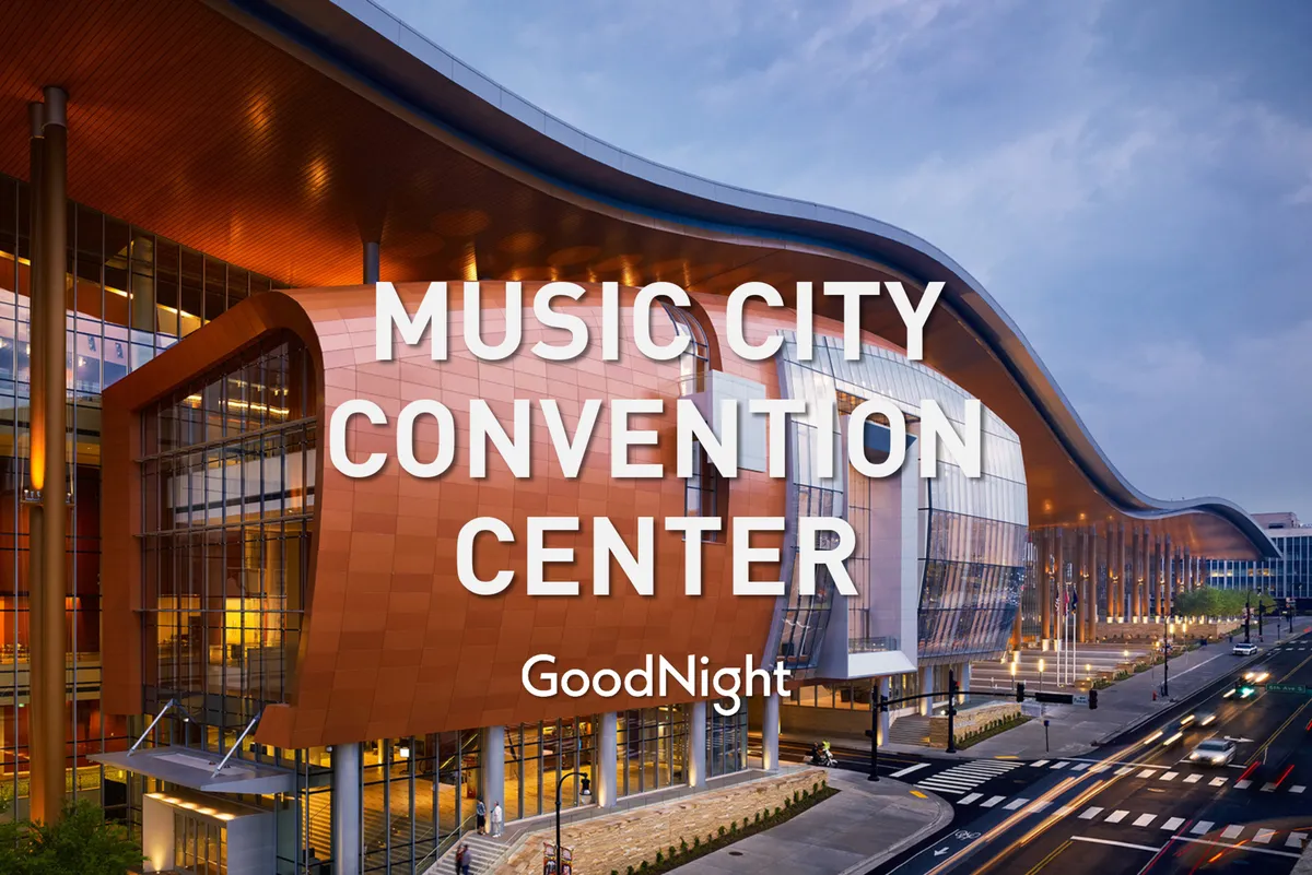 This image features the iconic curved roofline and vibrant orange facade of what appears to be a major conference and event venue, with glass walls and a welcoming exterior atmosphere. The setting suggests active use for conferences, trade shows, and networking events.