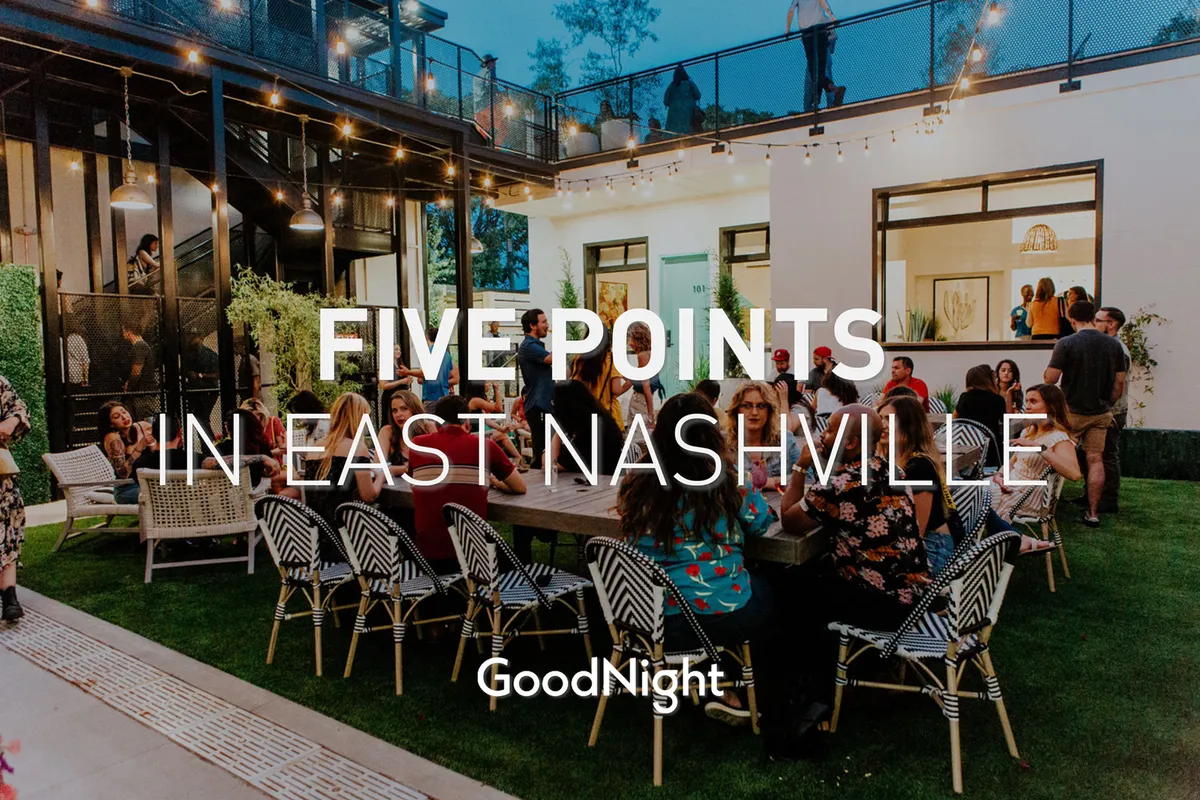A large outdoor dining table set beneath string lights, with people gathered and socializing in the lively evening atmosphere. The bistro lights add a festive touch, and the communal table encourages gatherings, making the space feel open, celebratory, and inviting.