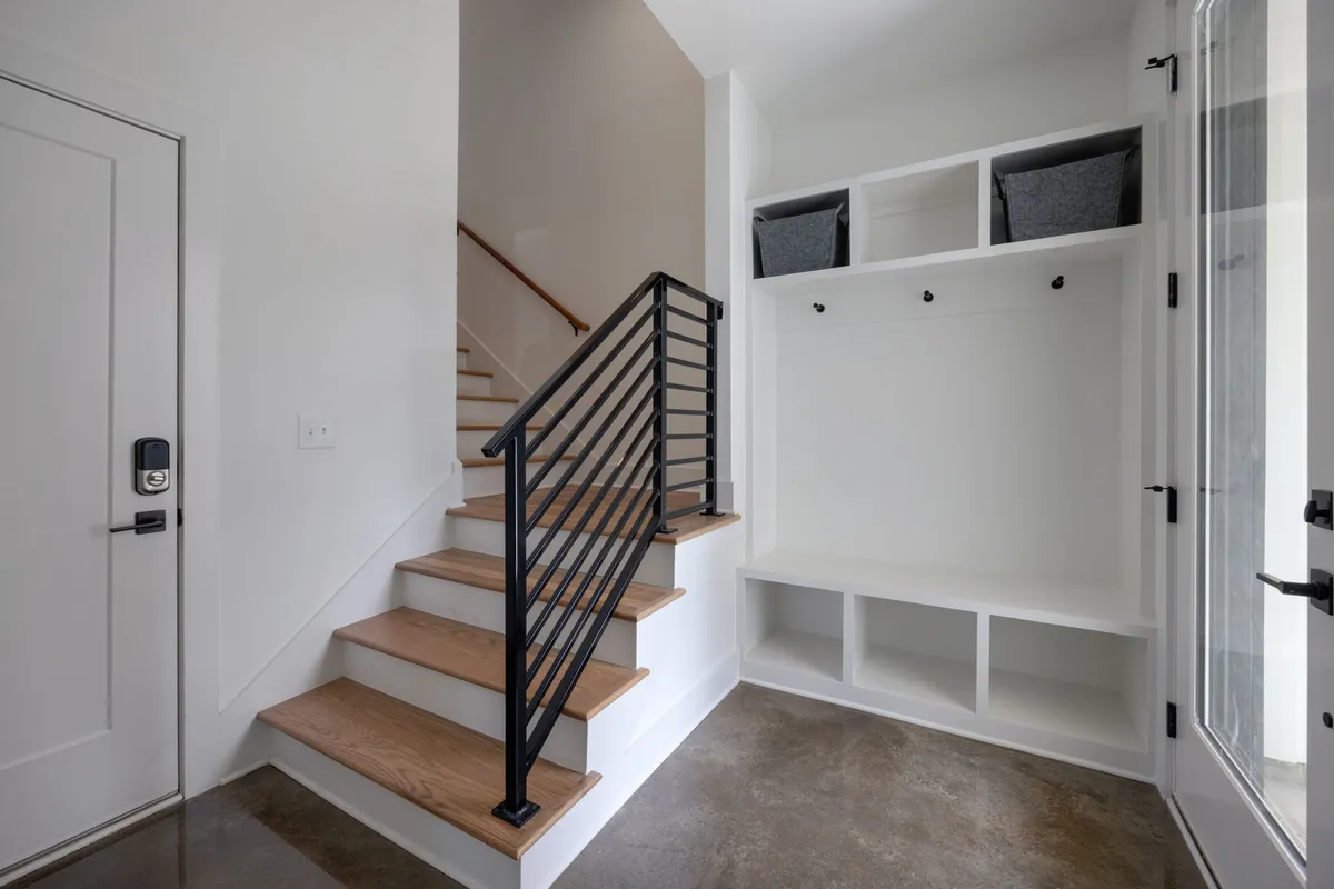 A view of the home's entryway and staircase, with a visible storage area that subtly hints at the capacity for personal belongings such as luggage or sports equipment. The inviting space suggests easy arrivals and departures, as well as seamless storage for urban explorers.