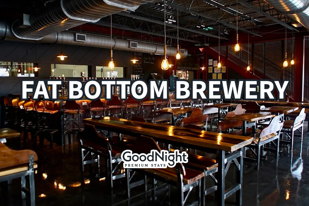 An interior shot of a lively brewery or bar area, featuring long wooden tables, a bar, and warm ambient lighting. The mood is casual and social, perfect for group gatherings, tastings, and relaxing after a day outdoors.